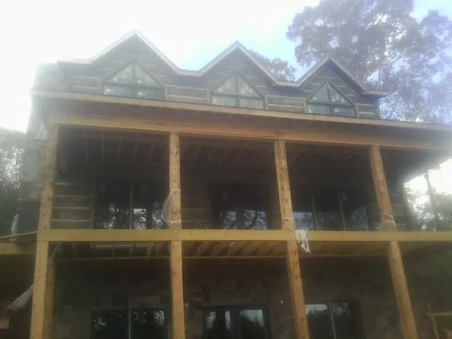 Dormers and porch framing on a large log home under construction — Roof Coating work by our crew in Harrah